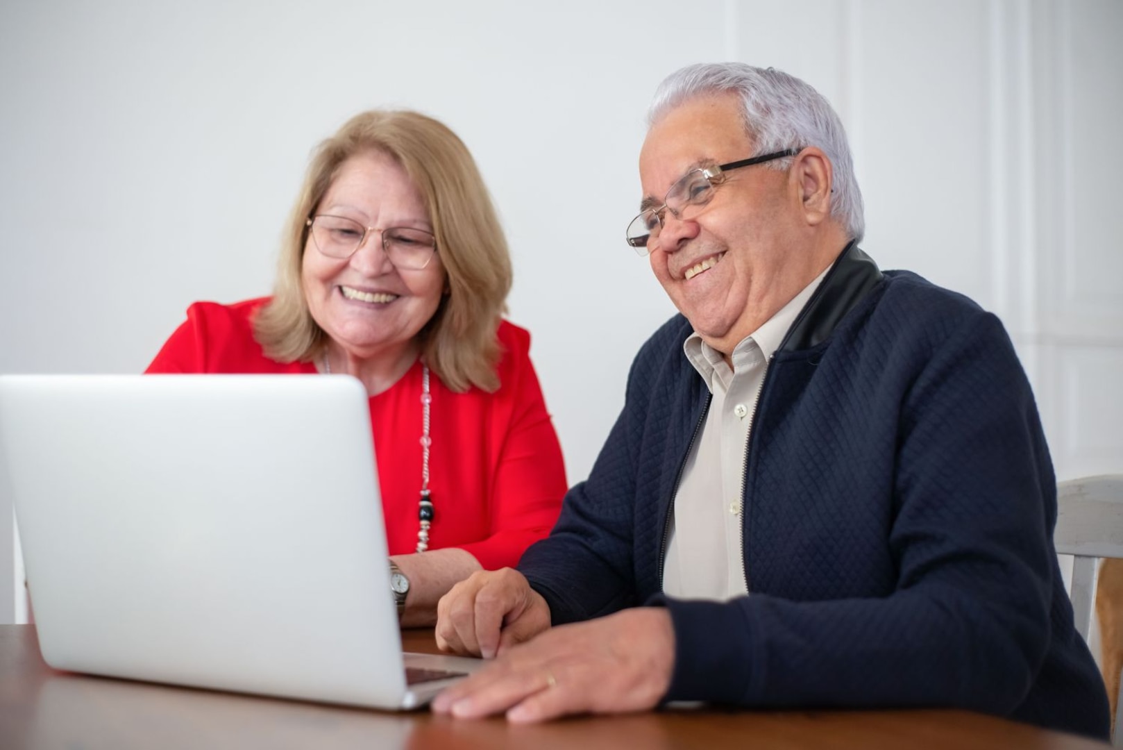 Man and woman sitting next to each other while smiling at a laptop