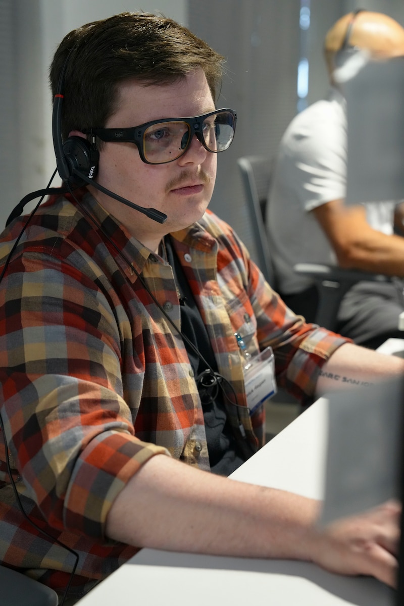 photo of US military member wearing a headset, civilian clothes working at a computer