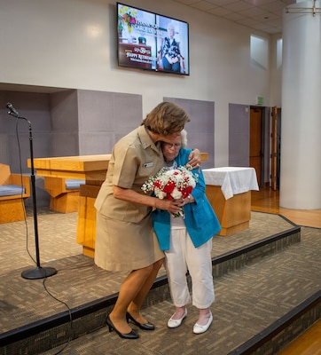 U.S. Navy Capt. Cindi Palacios, executive officer  of Naval Medical Center San Diego (NMCSD), presents a retirement memento to Carol Devine, executive assistant to the executive officer, during Devine’s retirement ceremony at NMCSD, June 24, 2026. Devine retired after 59 years of federal service, including 49 years at NMCSD. Throughout her career, Devine provided steadfast administrative leadership and continuity to generations of military and civilian leaders. The mission of NMCSD is to optimize health and enhance readiness. NMCSD employs more than 5,500 active-duty military personnel, civilians, and contractors in southern California to deliver exceptional care afloat and ashore. (U.S. Navy photo by Mass Communication Specialist 1st Class Marcus Stanley)