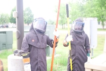 U.S. Air Force Airman 1st Class Mathew Manalo, electrical apprentice, 5th Civil Engineering squadron and Airman Frank Guzman Bunay, electrical apprentice, 5th Civil Engineering squadron pose before pulling elbows to power the secondary distribution center (SDC) at Fargo Air National Guard Base, North Dakota, June 1st, 2026. An SDC is a mobile or deployable electrical unit that accepts high-voltage primary power and steps it down into usable, low-voltage electricity for daily use in field environments.
