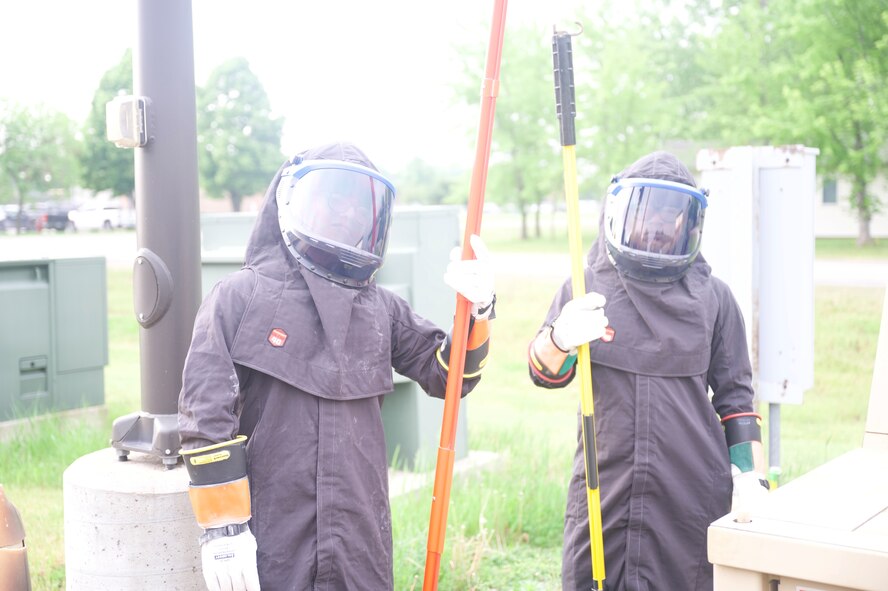 U.S. Air Force Airman 1st Class Mathew Manalo, electrical apprentice, 5th Civil Engineering squadron and Airman Frank Guzman Bunay, electrical apprentice, 5th Civil Engineering squadron pose before pulling elbows to power the secondary distribution center (SDC) at Fargo Air National Guard Base, North Dakota, June 1st, 2026. An SDC is a mobile or deployable electrical unit that accepts high-voltage primary power and steps it down into usable, low-voltage electricity for daily use in field environments.