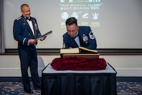 U.S. Air Force Col. James M. Clark observes as Master Sgt. Daniel Yuk signs his name in the Order of the Praetorian book.