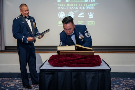 U.S. Air Force Col. James M. Clark observes as Master Sgt. Daniel Yuk signs his name in the Order of the Praetorian book.