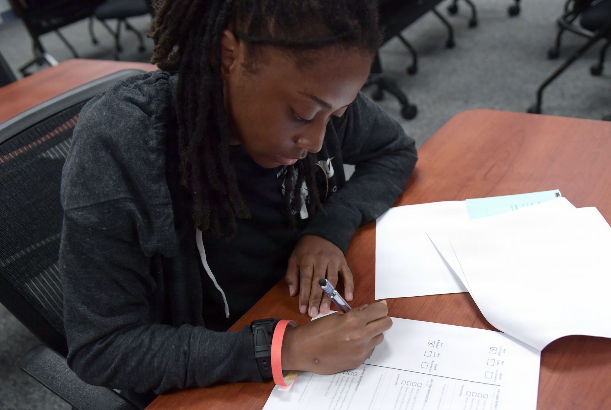 A woman fills out forms while sitting at a table.