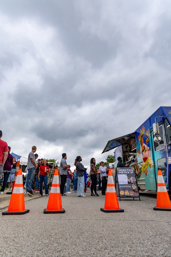 people standing in line at food truck with orange traffic cones in front