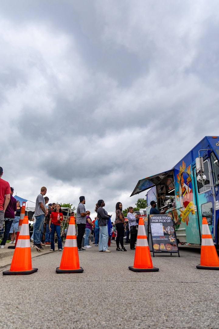people standing in line at food truck with orange traffic cones in front