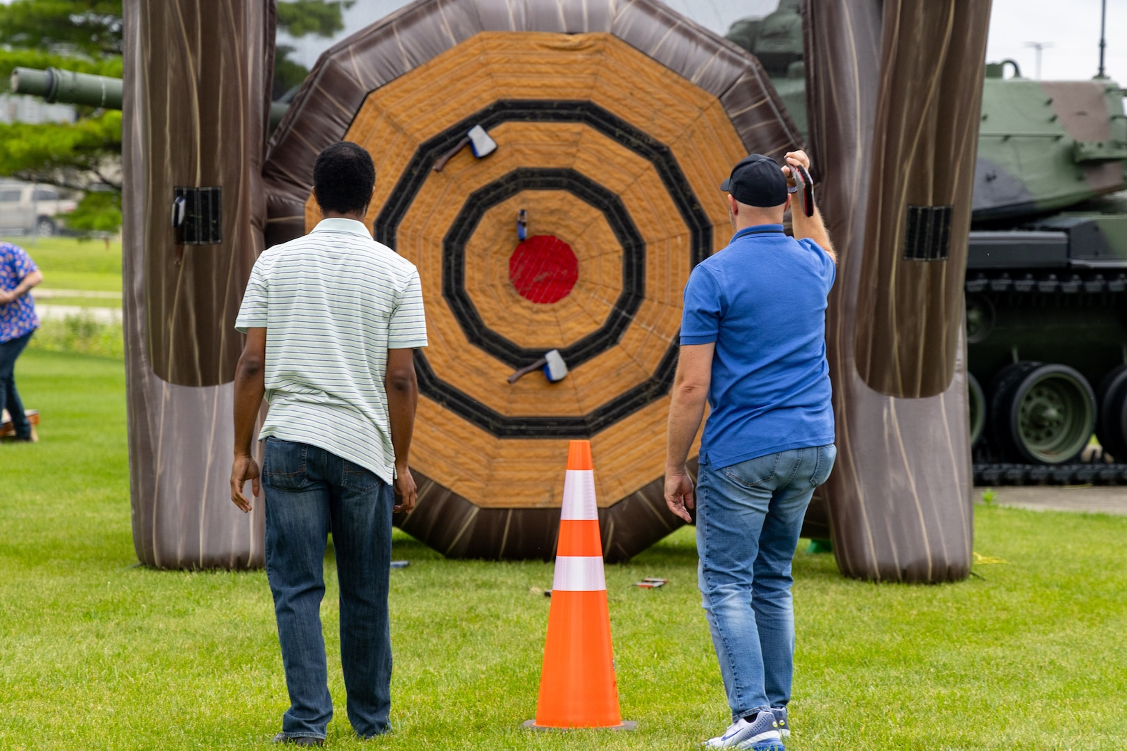 Two men facing large ax throwing inflatable.