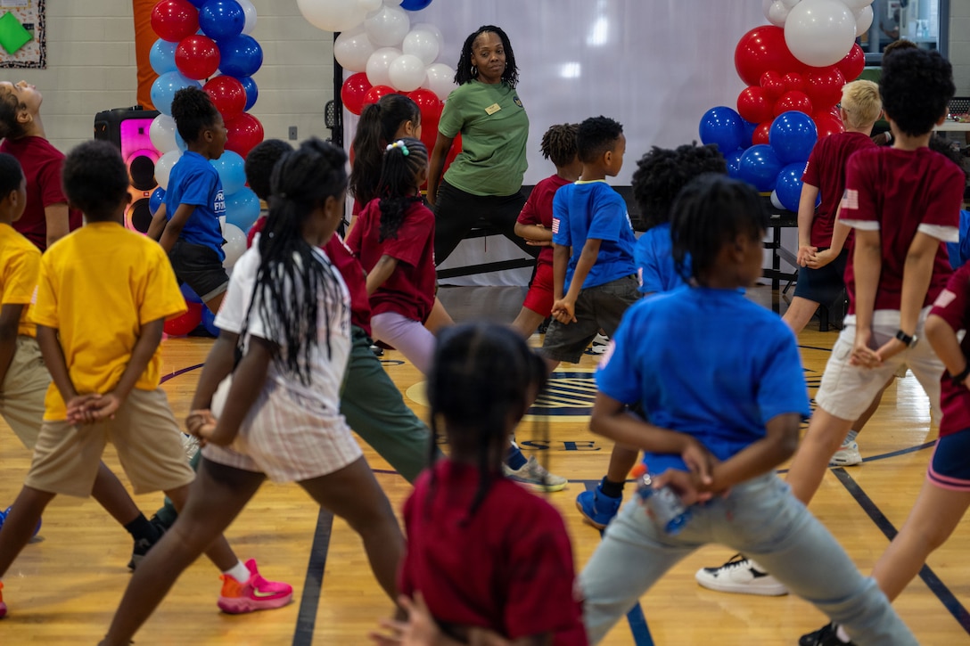 Vanessa Johnson, Joint Base Andrews Youth Center teen coordinator, leads students through stretches before the Presidential Fitness Test.