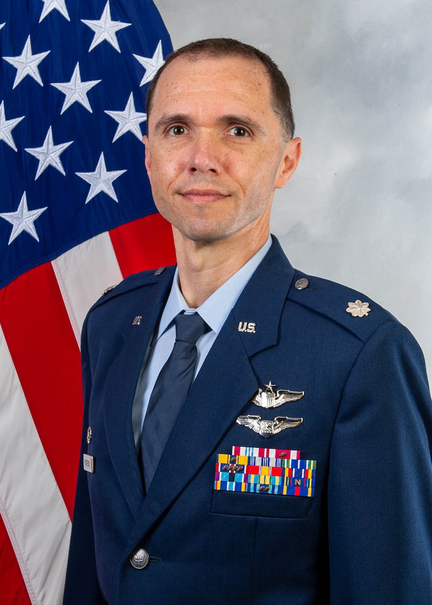 A man sits in front of a U.S. flag.