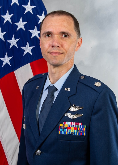 A man sits in front of a U.S. flag.