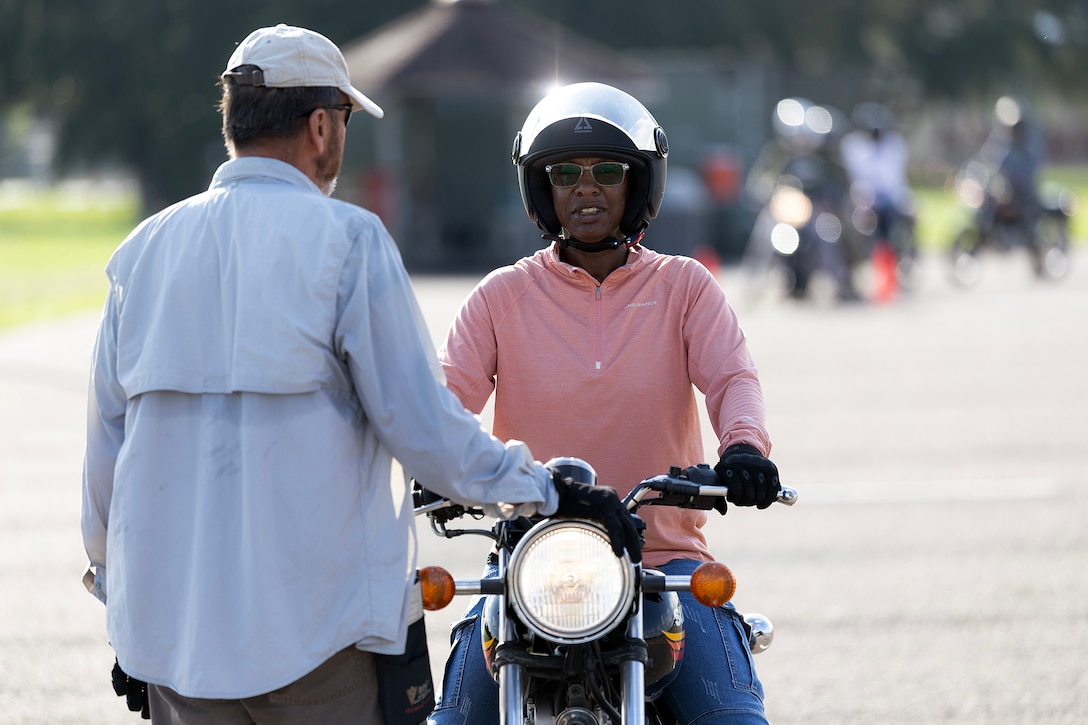 Retired Navy Chief Warrant Officer 4 Greg Wojciechowski, a Motorcycle Safety Foundation rider coach, speaks with Carletta McKenzie, a contracted supply material specialist for Blount Island Command, during a basic rider course June 25, 2026, at Marine Corps Support Facility Blount Island, Florida. The two-day course equipped novice riders with classroom instruction and hands-on training to develop rider proficiency and promote motorcycle safety. (Marine Corps photo by Dustin Senger)