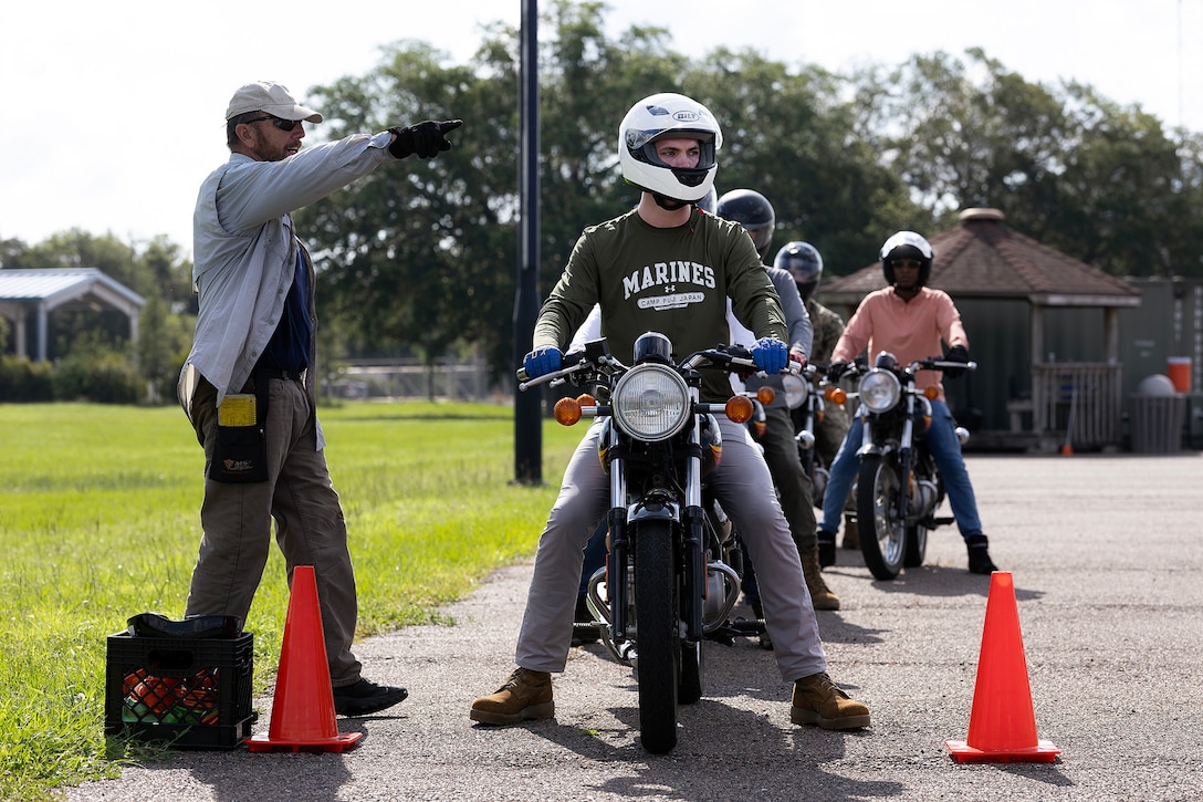 Retired U.S. Navy Chief Warrant Officer 4 Greg Wojciechowski, a Motorcycle Safety Foundation rider coach, directs Jacob Czepiel during a riding exercise in a basic rider course June 25, 2026, at Marine Corps Support Facility Blount Island, Florida. The two-day course equipped novice riders with classroom instruction and hands-on training to develop rider proficiency and promote motorcycle safety. (Marine Corps photo by Dustin Senger)