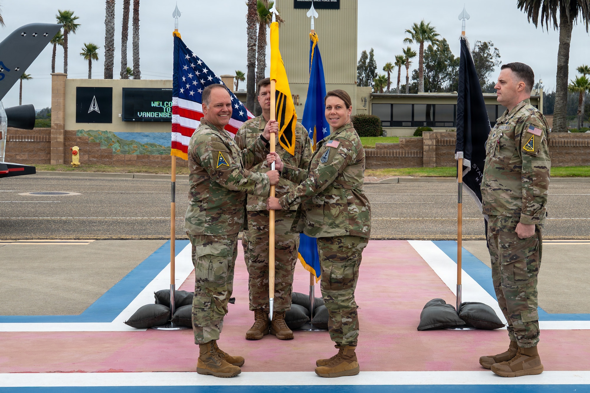 Four people stand while two of the people hold a flag together