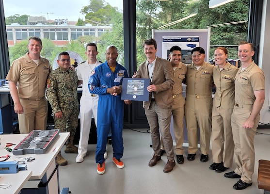 Naval Postgraduate School system engineering students are pictured with U.S. Navy Capt. Victor Glover, June 17, 2026, following a series of student research briefs on a variety of mission-driven topics including space weather effects on combat systems, carrier recovery tanker operations, and autonomous uncrewed surface vehicles. (U.S. Navy photo by Dan Linehan)