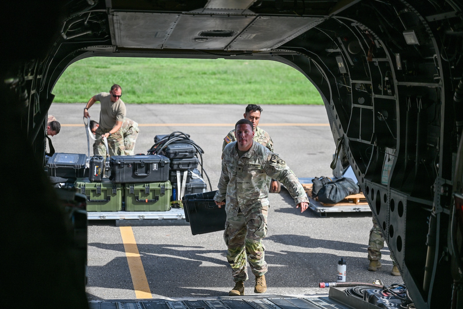 Military personnel load equipment onto a helicopter