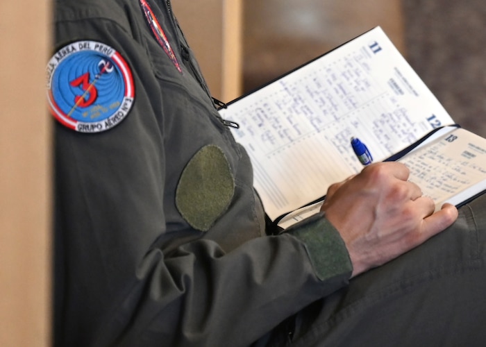 Peruvian air force (FAP) Lt. Col. Berly Briceño Velàsquez, FAP Department of the General Staff military group liaison, takes notes during the United States and Peru Airman-to-Airman Staff Talks, at Davis-Monthan Air Force Base, Arizona, June 16, 2026. The talks provided a forum to exchange best practices in aircraft operations, maintenance, logistics, training, and resource planning, strengthening interoperability and future cooperation between the two air forces. (U.S. Air Force photo by Staff Sgt. Abbey Rieves) Note this photo has been altered for operational security by blurring out written text.