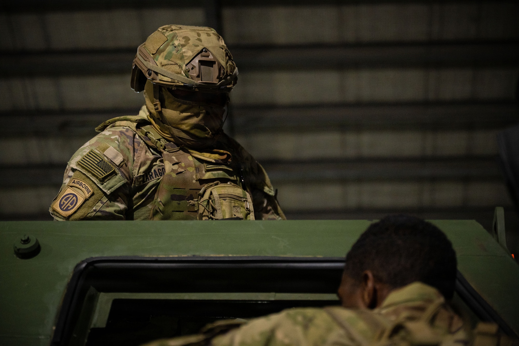 A soldier stands out of the top of a military vehicle