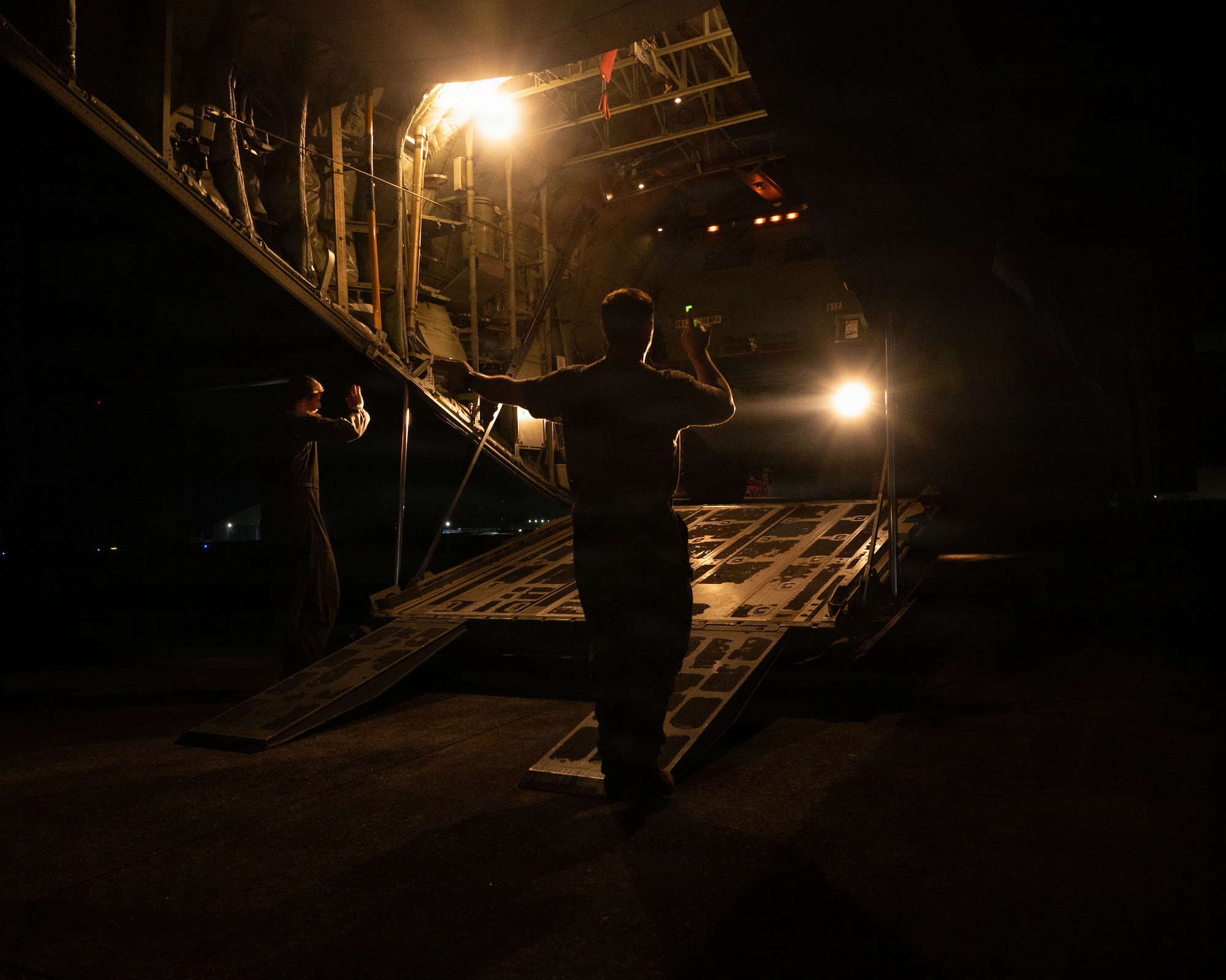 A servicemember gives hand signals to a military vehicle