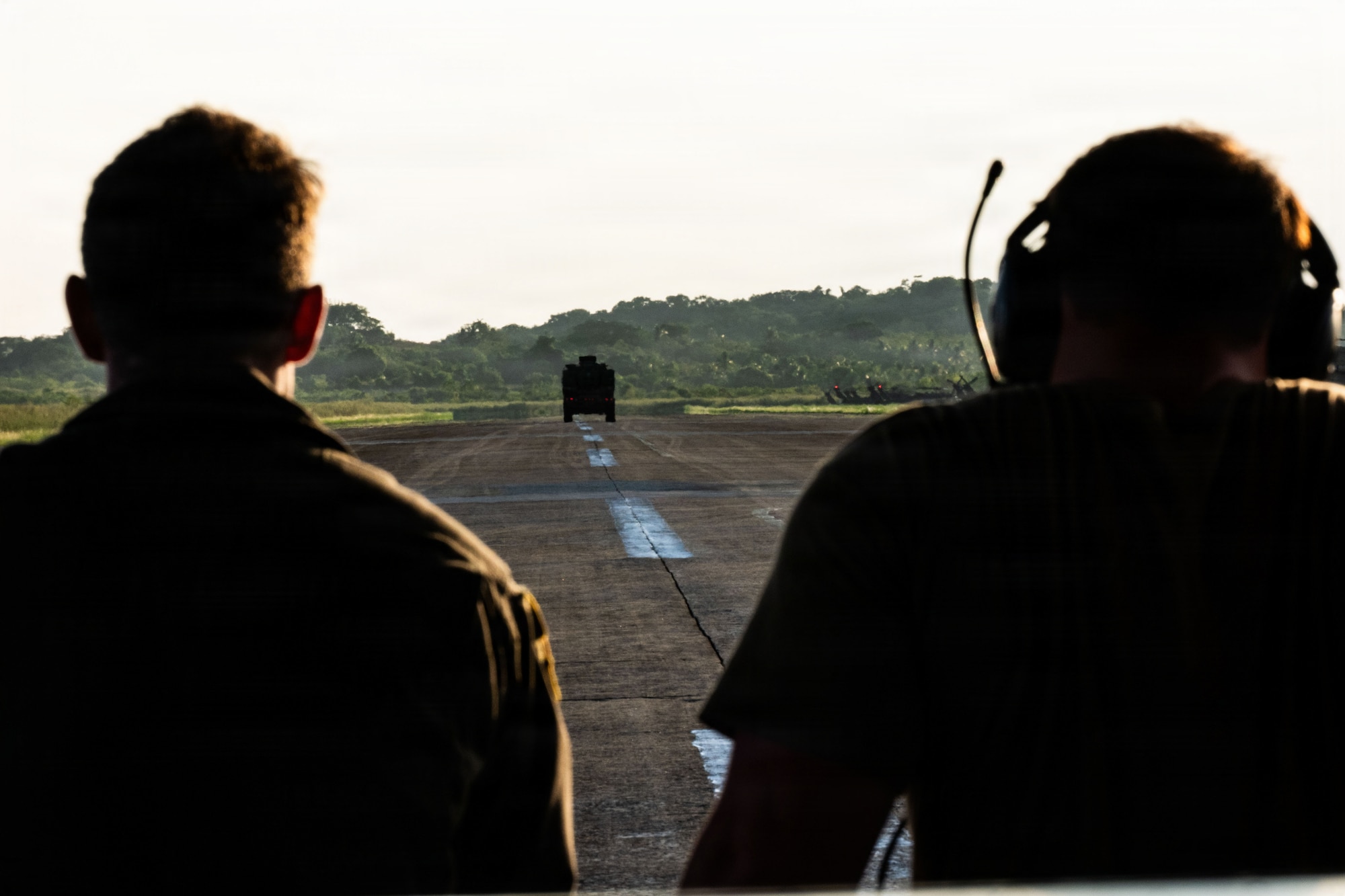 Servicemembers watch a military vehicle in the distance