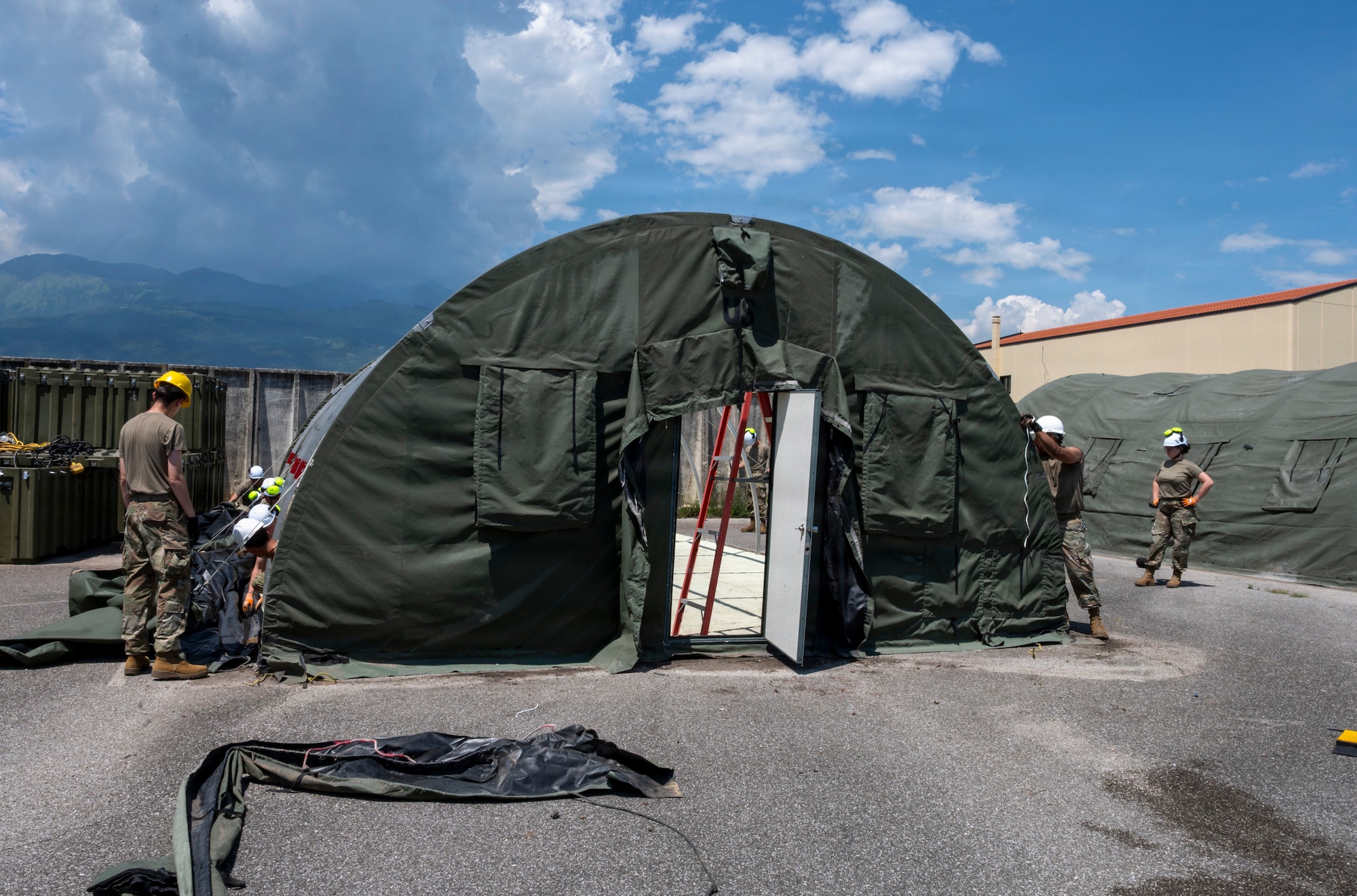 A group of men and women build a small system shelter.