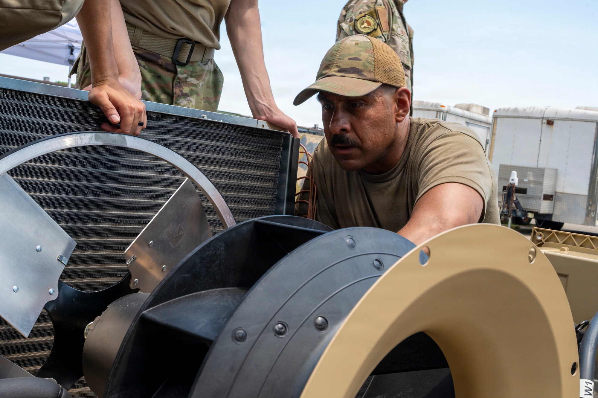 A man inspects the internal components of an HVAC unit.