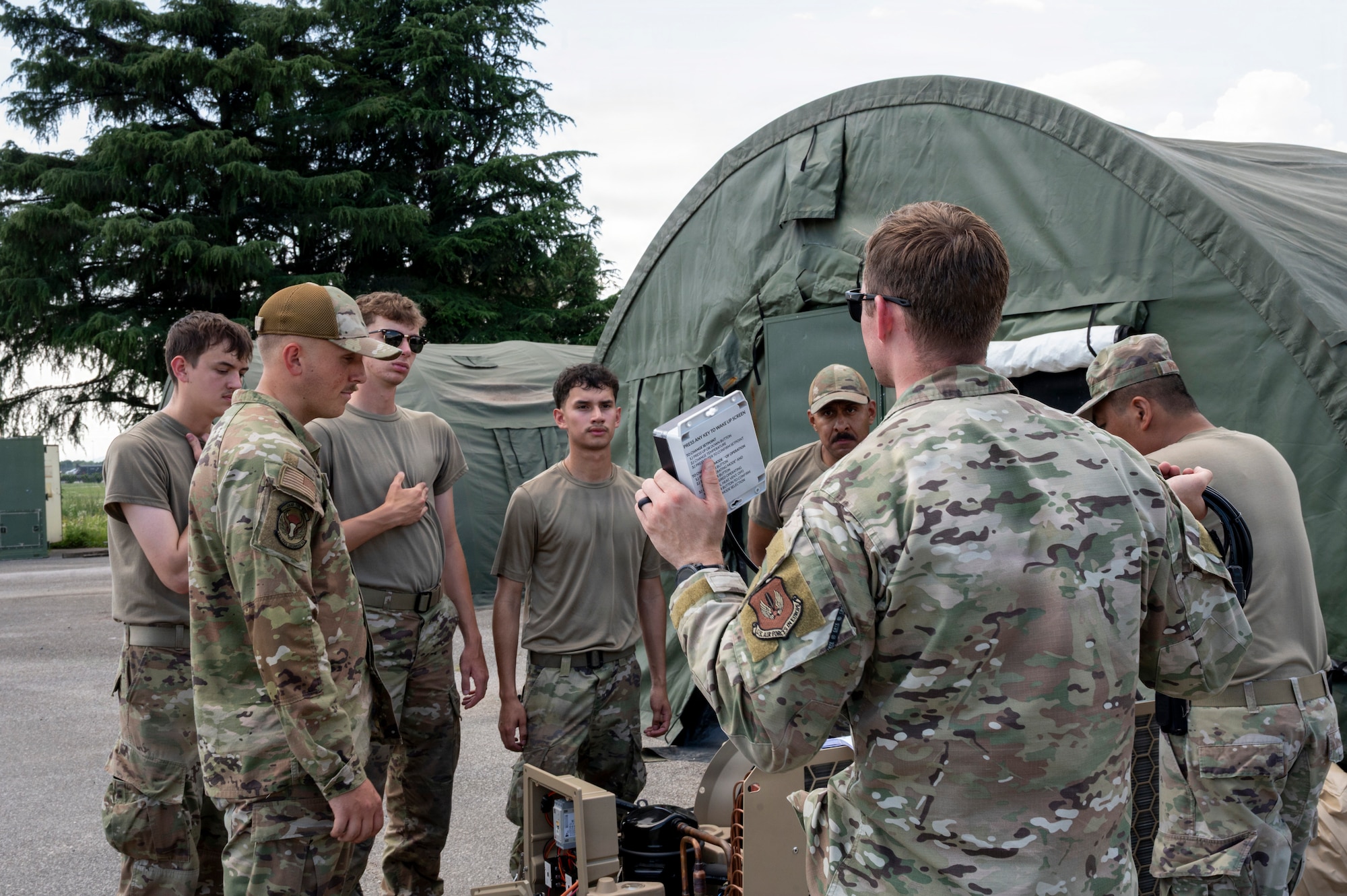A man teaches a group about an HVAC system outside.
