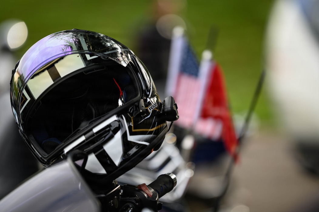 A motorcycle helmet rests on the handlebars of a motorcycle.