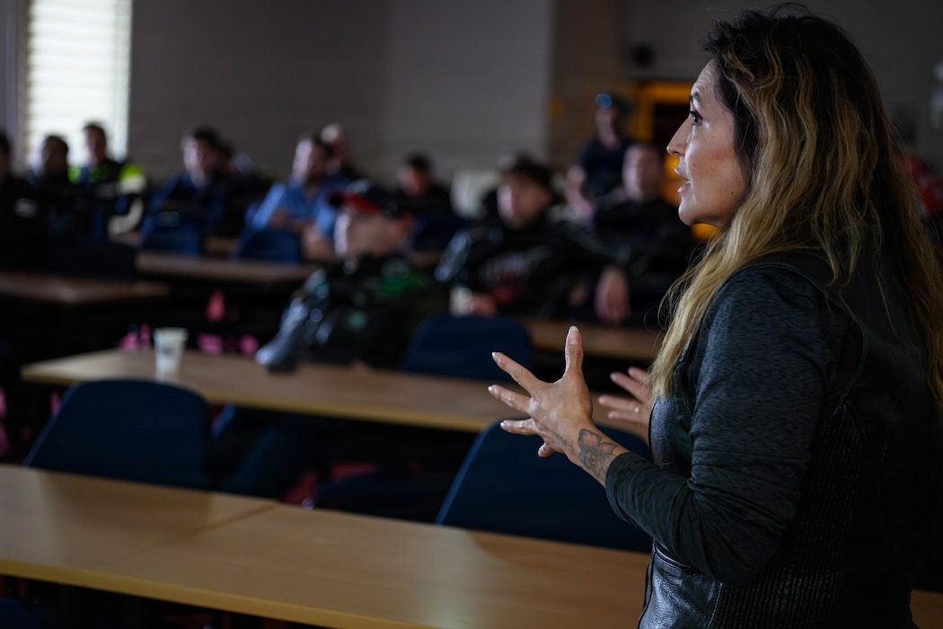 A woman speaks in front of a classroom of people.