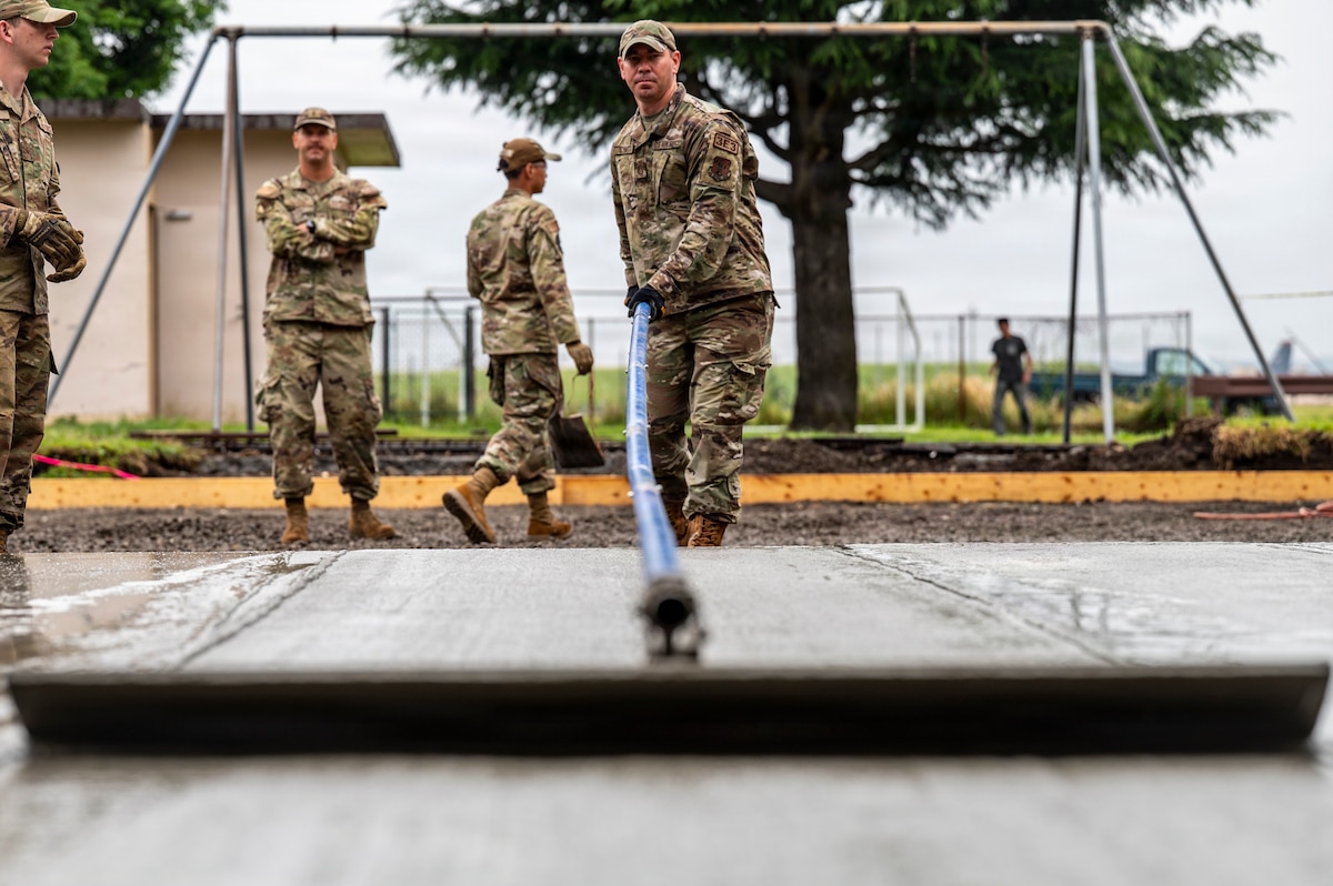 U.S. Air Force Master Sgt. Kevin Schmitt, a structures shop supervisor with the 121st Air Refueling Wing Civil Engineer Squadron, Ohio Air National Guard, rakes concrete during a concrete pour at Yokota Air Base, Japan, June 10, 2026. The 121st CE Squadron was deployed to Japan for a Deployment for Training, a temporary duty program in which Air National Guard CE Airmen deploy to active-duty bases to conduct training by assisting with real-world projects. (U.S. Air National Guard photo by Airman Phyel Richardson)