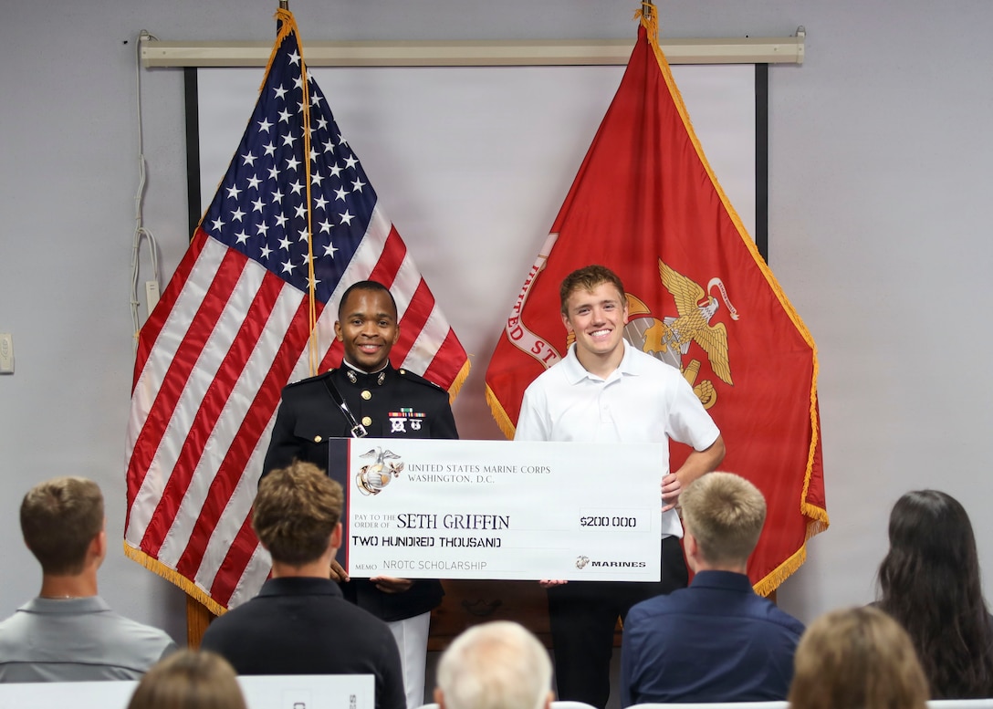 U.S. Marine Corps Capt. Kameron Gaskin, executive officer, Recruiting Station San Antonio, presents a Naval Reserve Officers Training Corps (NROTC) scholarship to Seth Griffin during a scholarship presentation ceremony at the former Military Entrance Processing Station building in San Antonio, Texas, May 23, 2026. The ceremony recognized students selected to receive NROTC scholarships, providing opportunities to pursue higher education while preparing for future service as Marine Corps and Navy officers. (U.S. Marine Corps photo by Staff Sgt. Jacqueline Peguero-Montes)