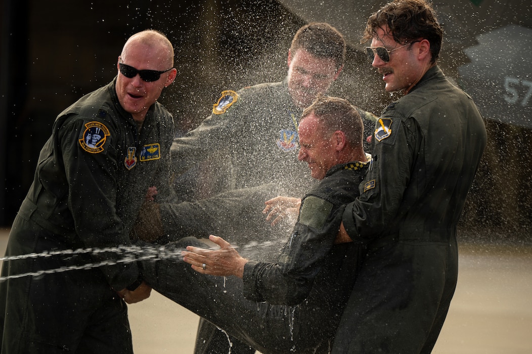 U.S. Air Force Col. Christian Bergtholdt, 325th Fighter Wing commander, is sprayed with water with other airmen laughing.