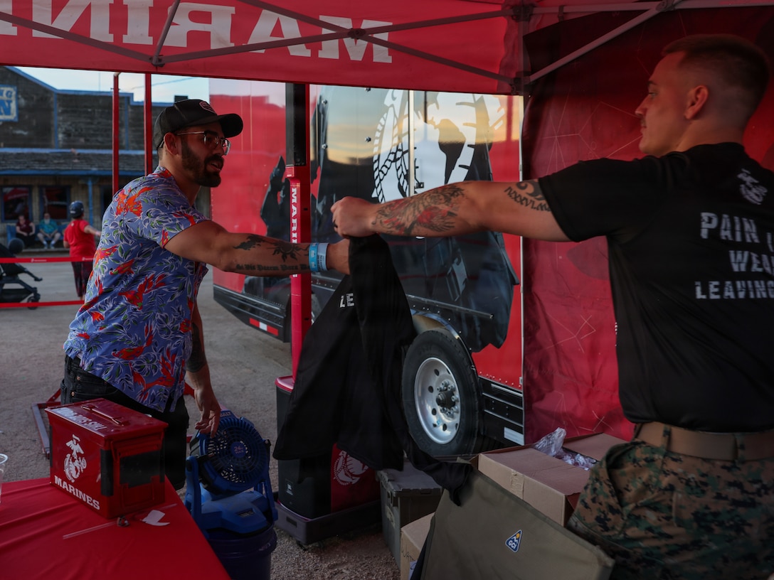 U.S. Marine Corps Staff Sgt. Cole Jhaner, a recruiter with Recruiting Station Phoenix, 8th Marine Corps District motivates an attendee during Ostrich Festival in Chandler, Arizona, March 13, 2026. Ostrich Festival brings in over 300,000 attendees over its duration. Marines use the Marine pull-up bar challenge and the Laser Shooting range to interact with event attendees and talk to them about Marine Corps opportunities. (U.S. Marine Corps photo by Lance Cpl. Abram Maestre)