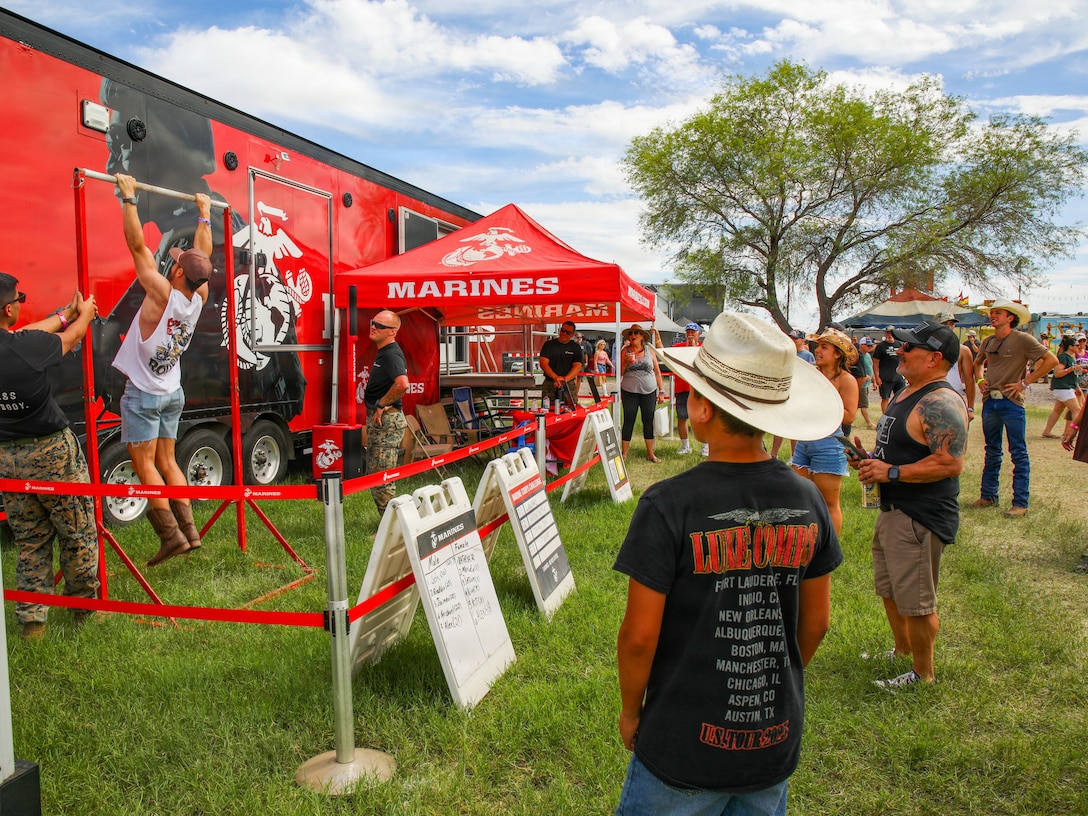 U.S. Marines with 8th Marine Corps District, Western Recruiting Region, interact with attendees during the Country Thunder Music Festival, in Florence, Ariz. April, 10, 2026. Country Thunder is a music festival that hosts several concerts and brings in 35,000 people per day. Arizona Marines utilized the pull-up bar to engage with event attendees and talk to them about Marine Corps career opportunities. (U.S. Marine Corps photo by Lance Cpl. Abram Maestre)