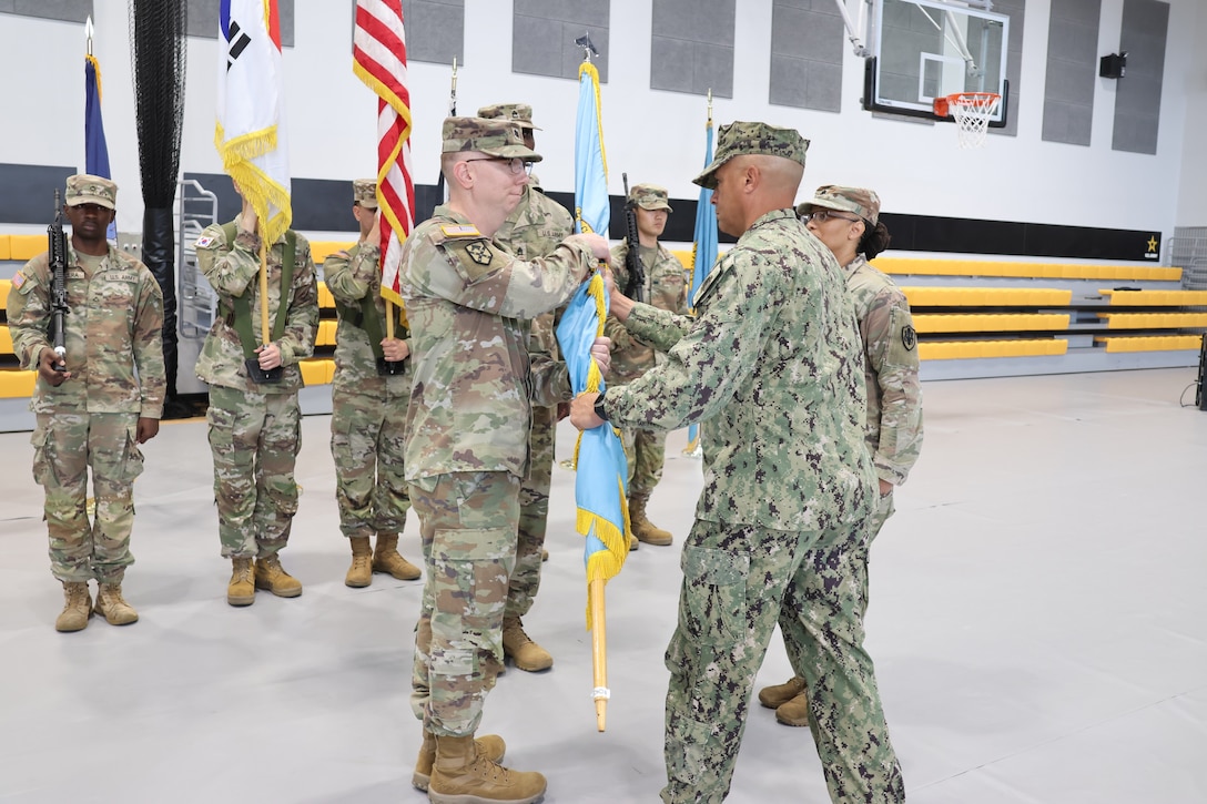 A unit guidon is passed from one person to the other.