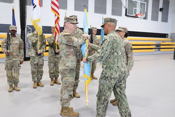 A unit guidon is passed from one person to the other.