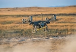 A Lorica Technologies Inc. Mule 28 unmanned aerial system carries a live, primed M1A3 Bangalore torpedo toward a concertina wire obstacle moments before release June 22, 2026, on Range 22 at Orchard Combat Training Center, Idaho. Soldiers with B Company, 741st Brigade Engineer Battalion, 41st Infantry Brigade Combat Team, conducted the proof-of-concept drone-delivered breach as the culmination of months of planning by the battalion's drone working group. The Mule 28 was custom-built by the Ashland, Oregon, manufacturer to lift and release the demolition charge. Photo by Maj. W. Chris Clyne.
