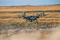 A Lorica Technologies Inc. Mule 28 unmanned aerial system carries a live, primed M1A3 Bangalore torpedo toward a concertina wire obstacle moments before release June 22, 2026, on Range 22 at Orchard Combat Training Center, Idaho.