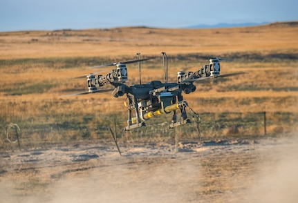 A Lorica Technologies Inc. Mule 28 unmanned aerial system carries a live, primed M1A3 Bangalore torpedo toward a concertina wire obstacle moments before release June 22, 2026, on Range 22 at Orchard Combat Training Center, Idaho.