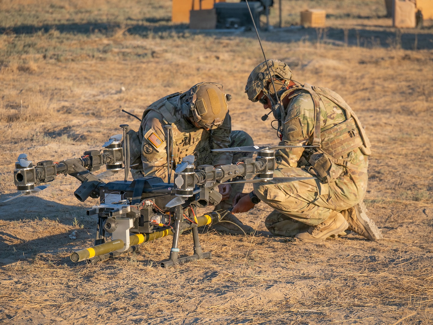 Sgt. 1st Class Raynaldo Villarreal, left, and 1st Sgt. Joshua Martin prime a live M1A3 Bangalore torpedo by connecting shock tube to the charge before a drone-delivered breach attempt against a concertina wire obstacle June 22, 2026, on Range 22 at Orchard Combat Training Center, Idaho.