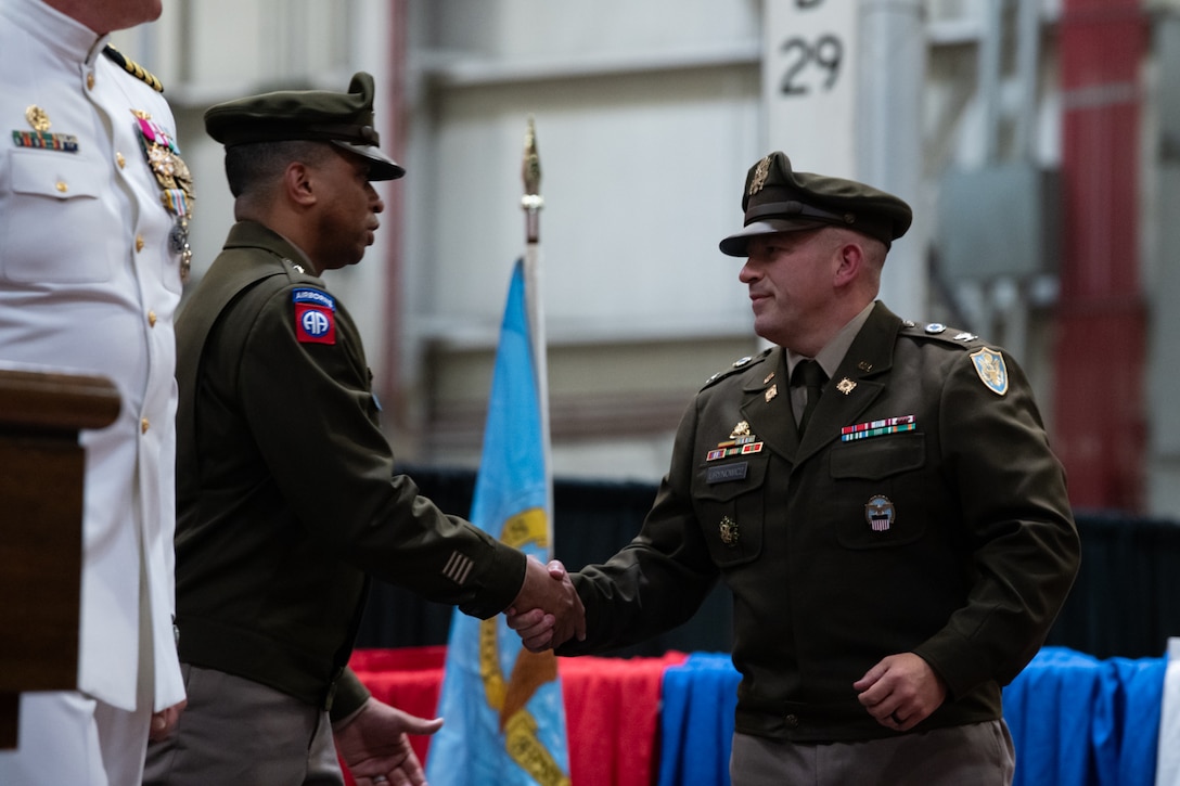 Two men in military uniforms shake hands