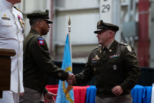 Two men in military uniforms shake hands