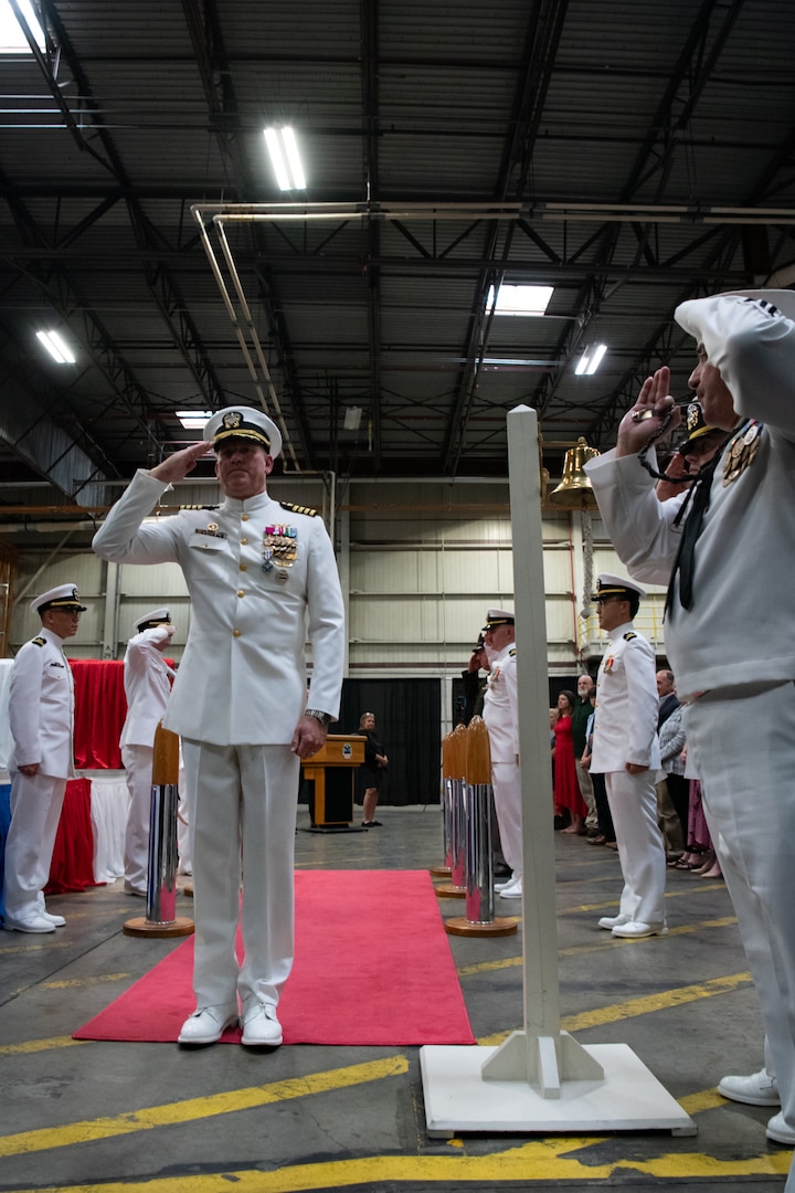 A man wearing a military uniform is saluted by other men as he walks down a red carpet.