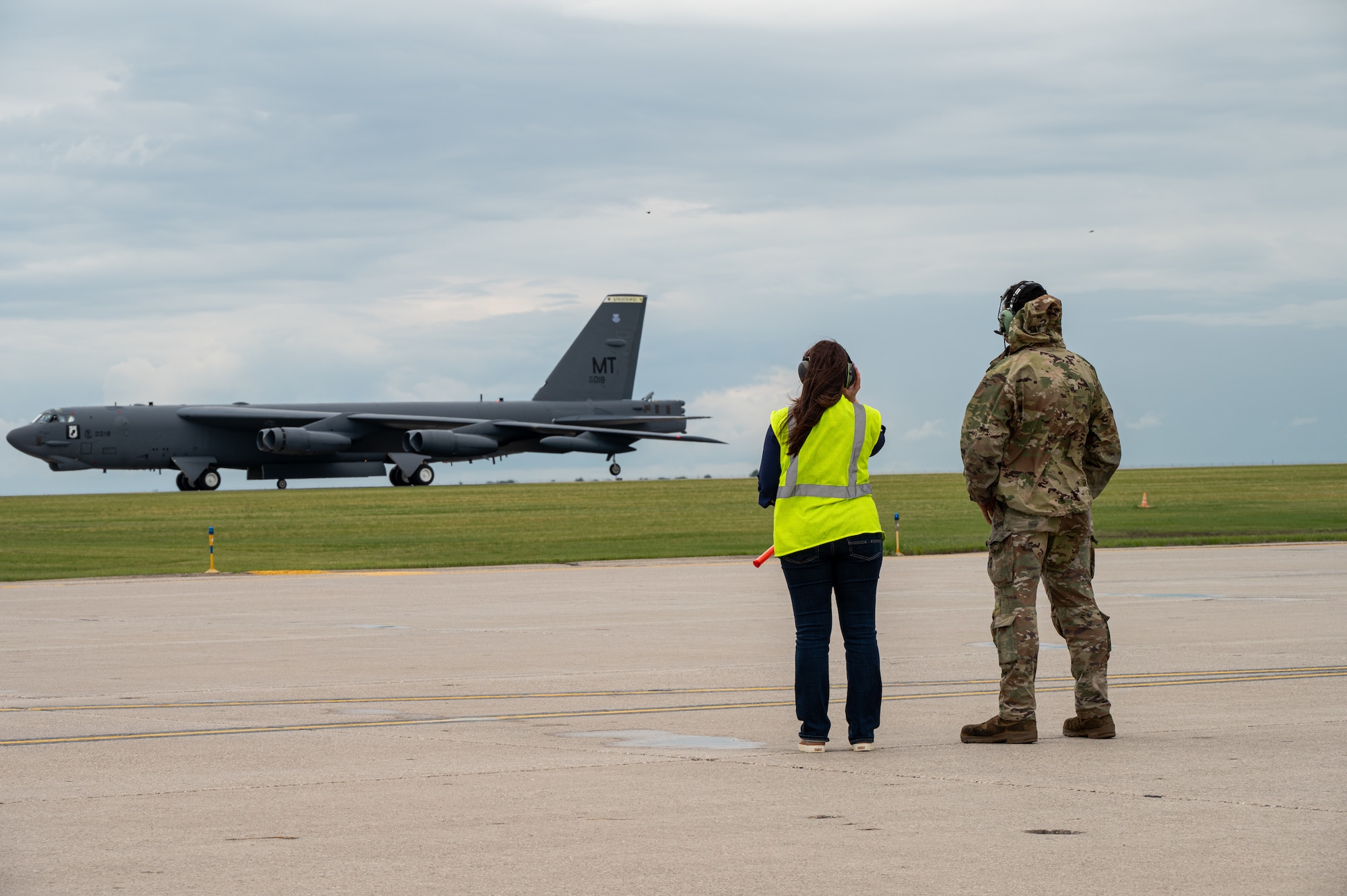 Two people watch an aircraft land.