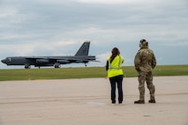 Two people watch an aircraft land.