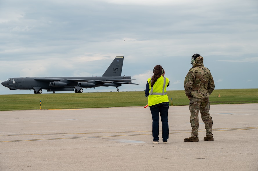 Two people watch an aircraft land.