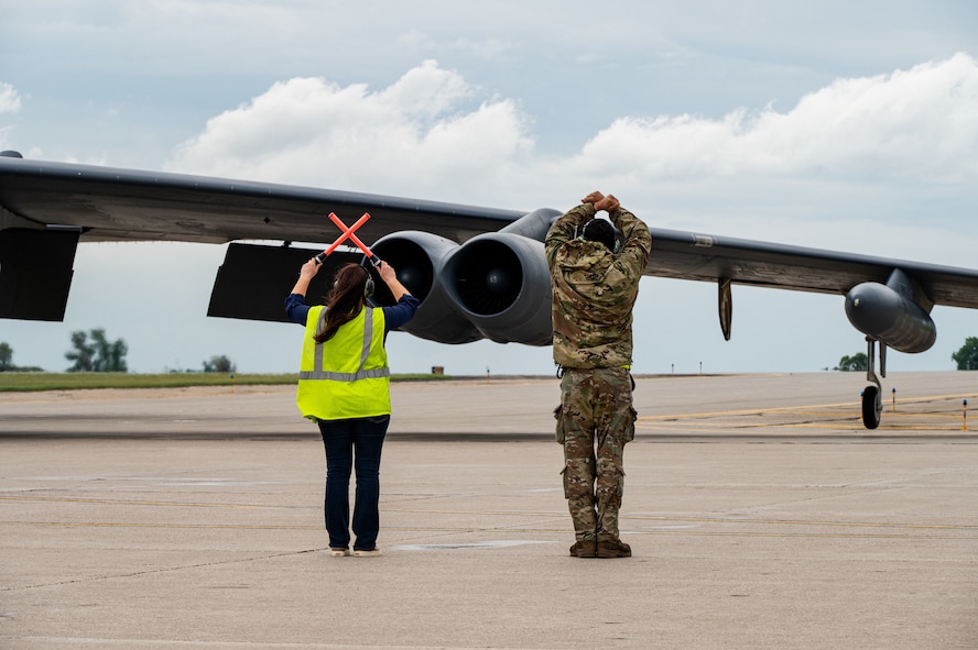 Two people guide an aircraft in.