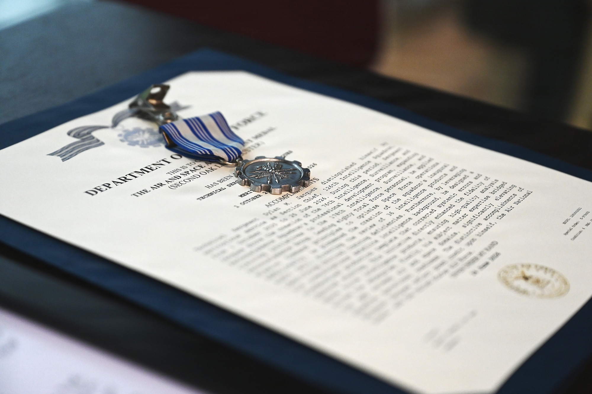 An Air and Space Achievement Medal for U.S. Air Force Tech. Sgt. Dylan Jacques, an intelligence analyst assigned to the 126th Intelligence Squadron at Springfield-Beckley Air National Guard Base transferred to the 76th Intelligence, Surveillance and Reconnaissance Squadron in a historic ceremony June 26, 2026 sits on a table. This marks the first time an Airman in the Air National Guard has been authorized to transfer to the Space Force without completing their existing service commitments to the Guard. (U.S. Air National Guard photo by Shane Hughes)
