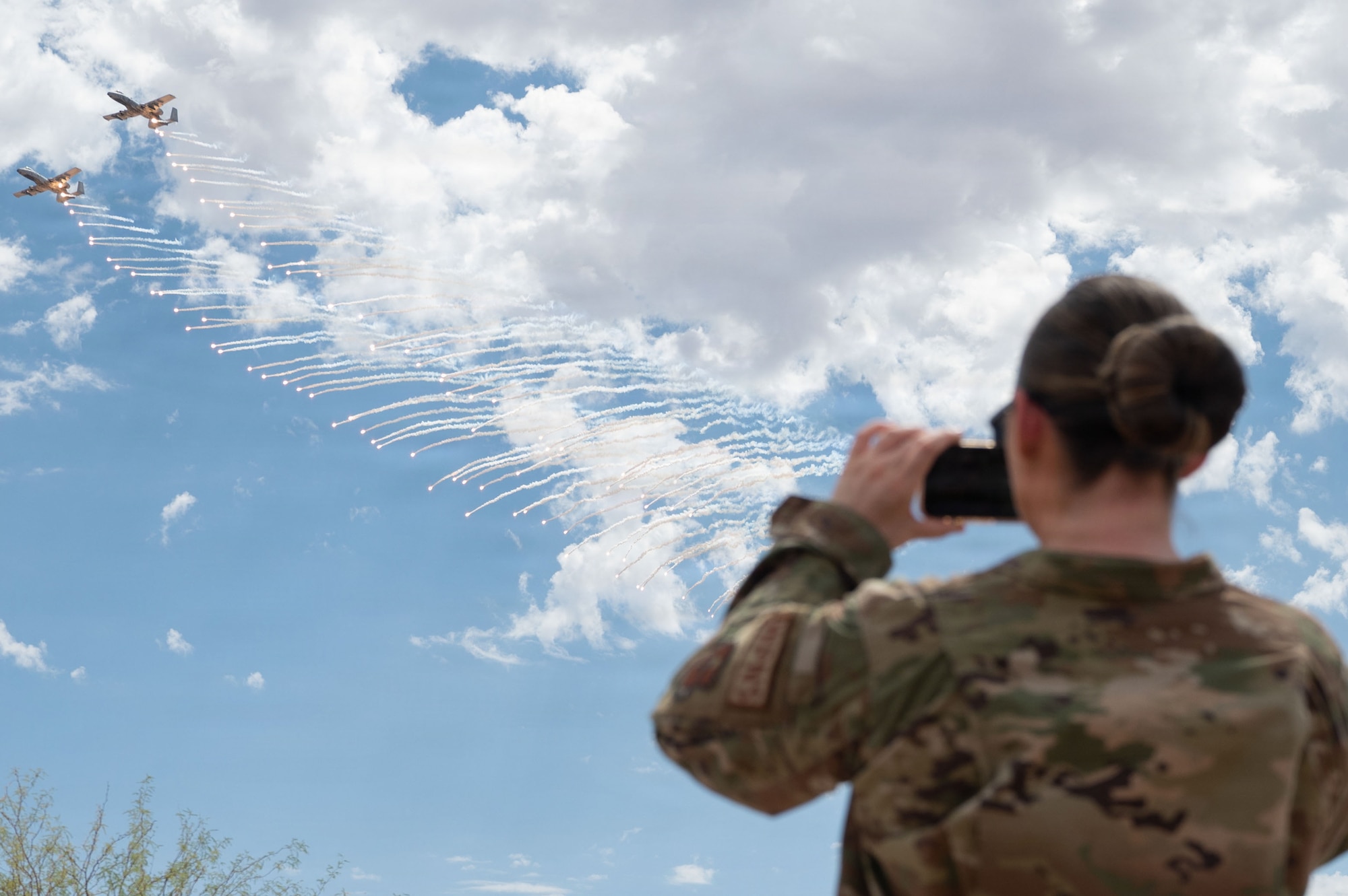 A U.S. Airman photographs an A-10C Thunderbolt II aircraft at the Barry M. Goldwater Range near Gila Bend, Arizona, June 25, 2026. The aircraft deploys flares during an aerial demonstration for attendees of the final A-10 Range Day.  (U.S. Air Force photo by Airman Najzee Kuzu)