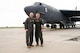 Two men stand in from of an aircraft.