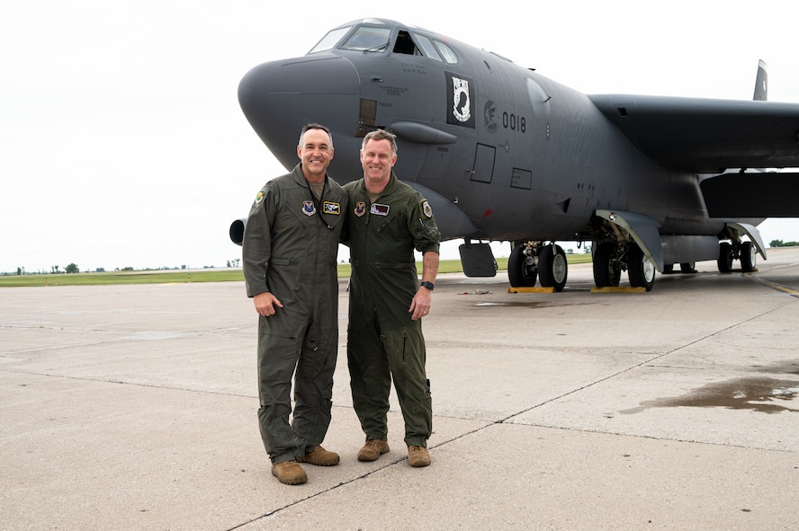 Two men stand in from of an aircraft.